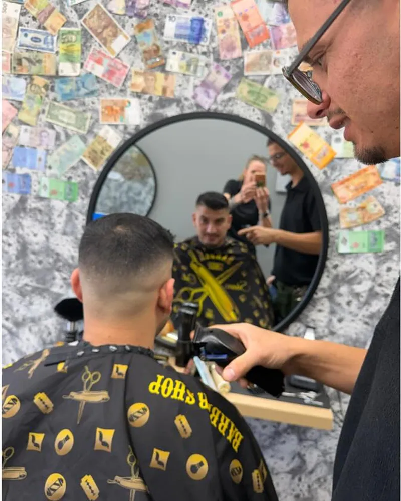 Barber finishing a fade with clippers in the chair at Airlie Cutz